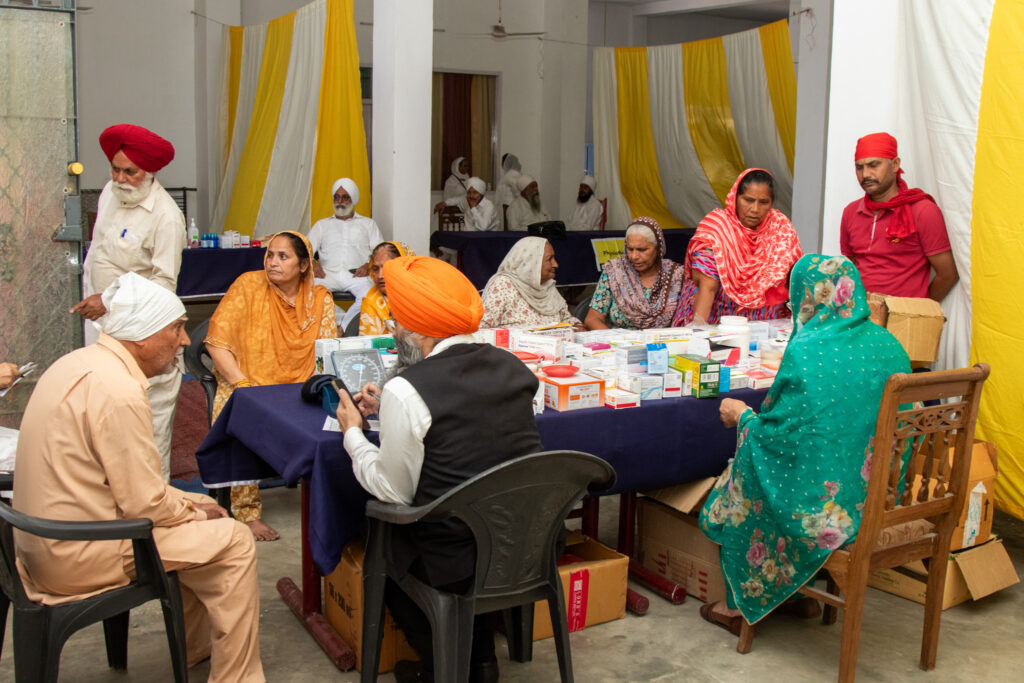 2026-free-medical-camp-bakhshish-international-charitable-society-nussi-jalandhar-03 Physician consulting patients and prescribing medicine at Gurdwara Bakhshish Dham free medical camp 2026