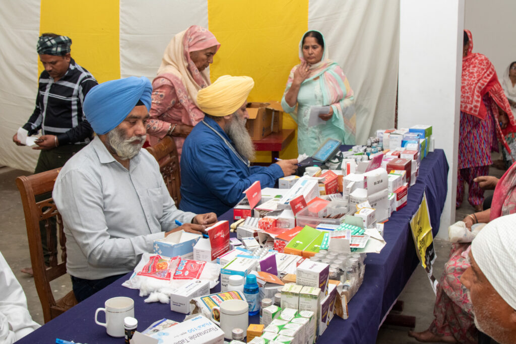 2026-free-medical-camp-bakhshish-international-charitable-society-nussi-jalandhar-05 Physician consulting patients and prescribing medicine at Gurdwara Bakhshish Dham free medical camp 2026
